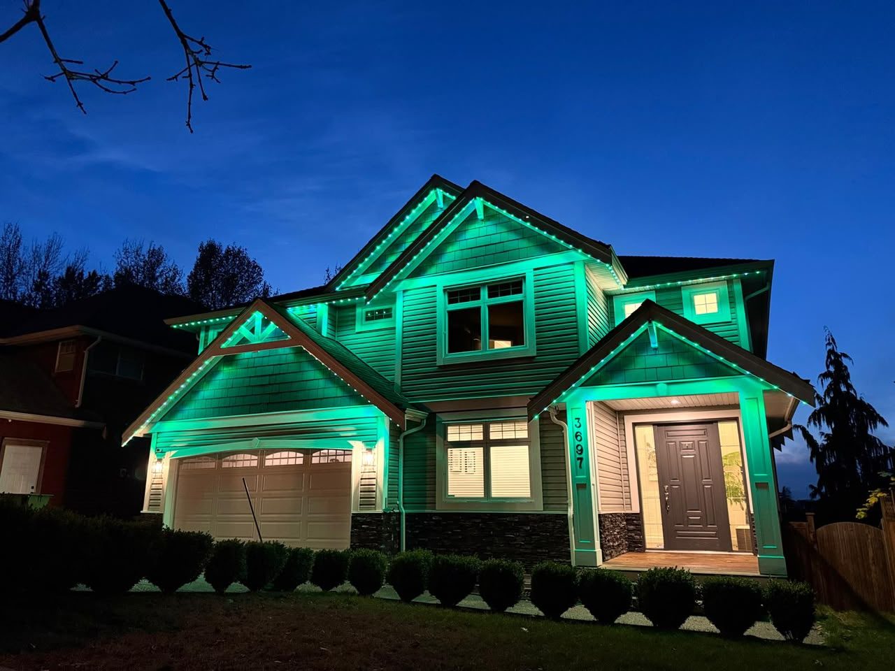A craftsman home with every gable and porch column outlined in emerald.