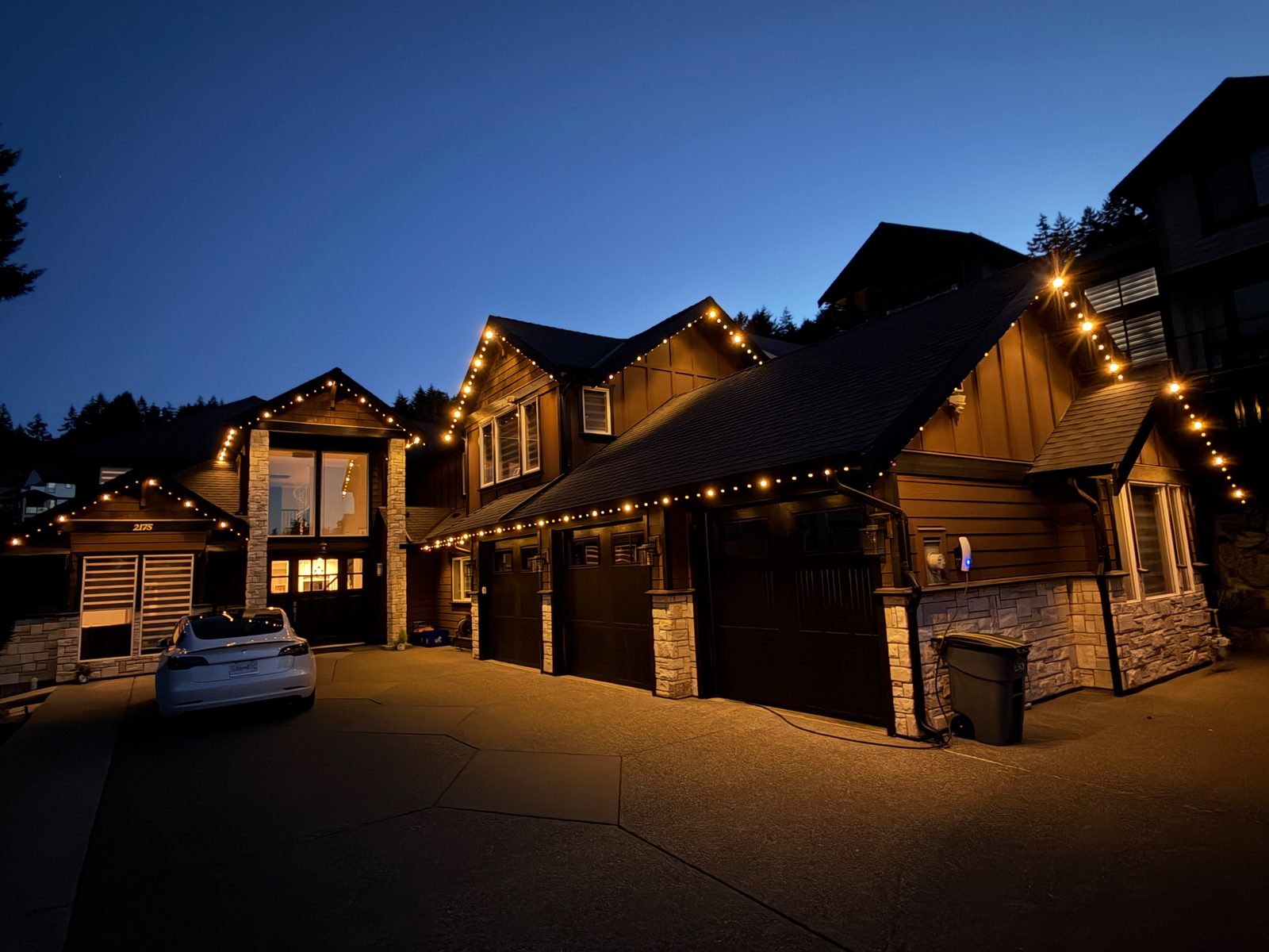 A large craftsman home at dusk with warm white lighting along the rooflines.