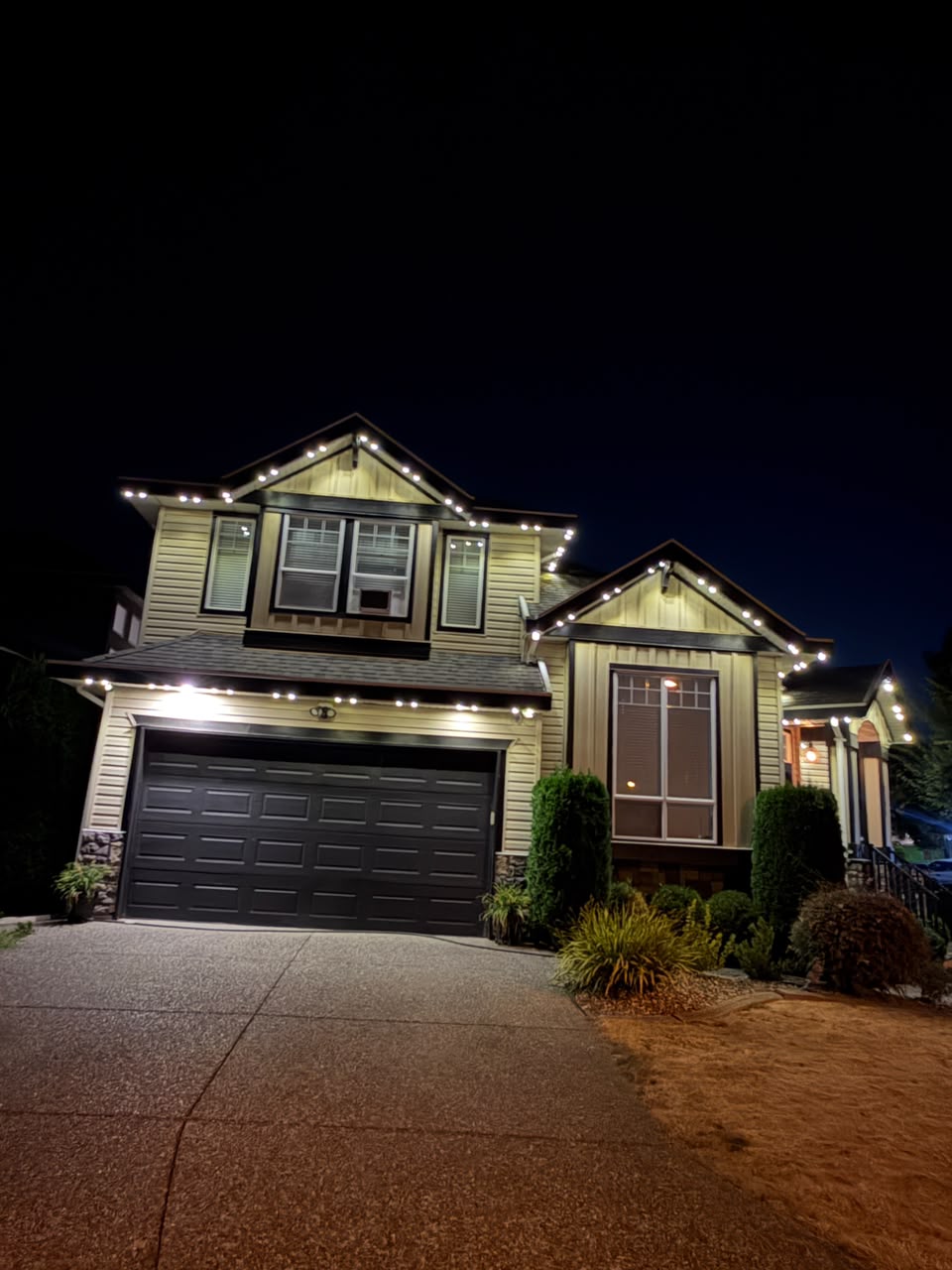 Multi-gable luxury estate outlined in warm white architectural lighting.