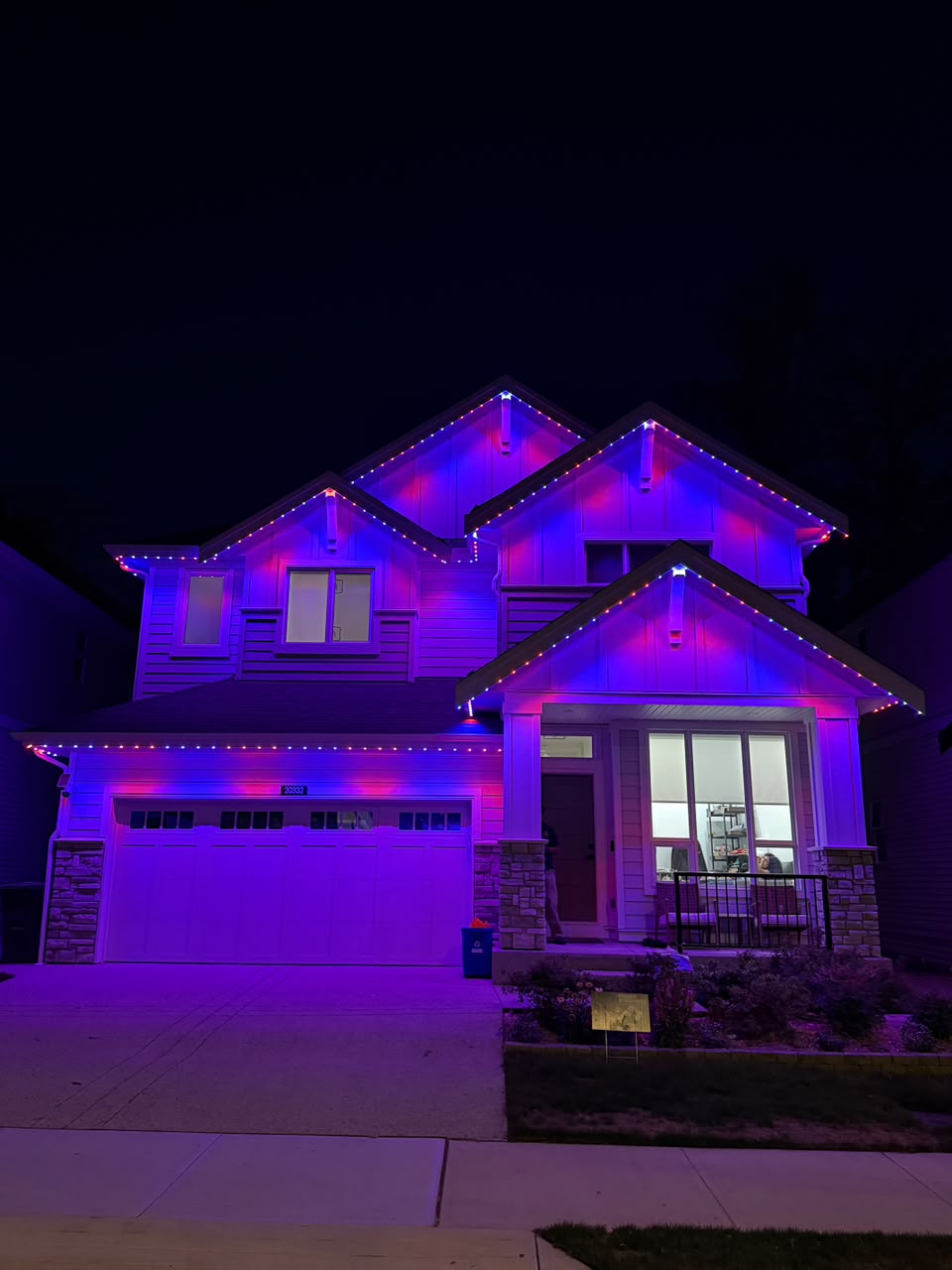 Vibrant royal blue and magenta party lighting on two-story home.