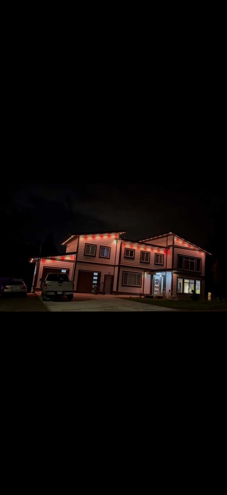 A large building lit in red and white along every roofline at night.